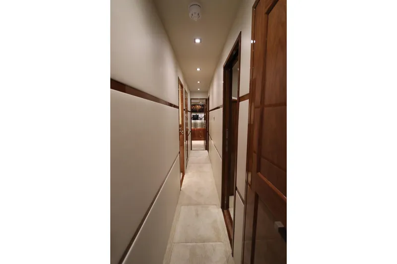 Slide: The Image of Hallway inside 2017 Viking 80 Enclosed Bridge yacht, featuring elegant wood paneling and modern lighting. - 21