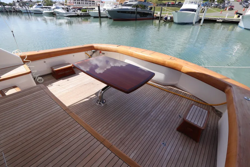 Slide: The Image of Luxurious 2017 Viking 80 Enclosed Bridge yacht deck with polished wood table and marina view. - 46