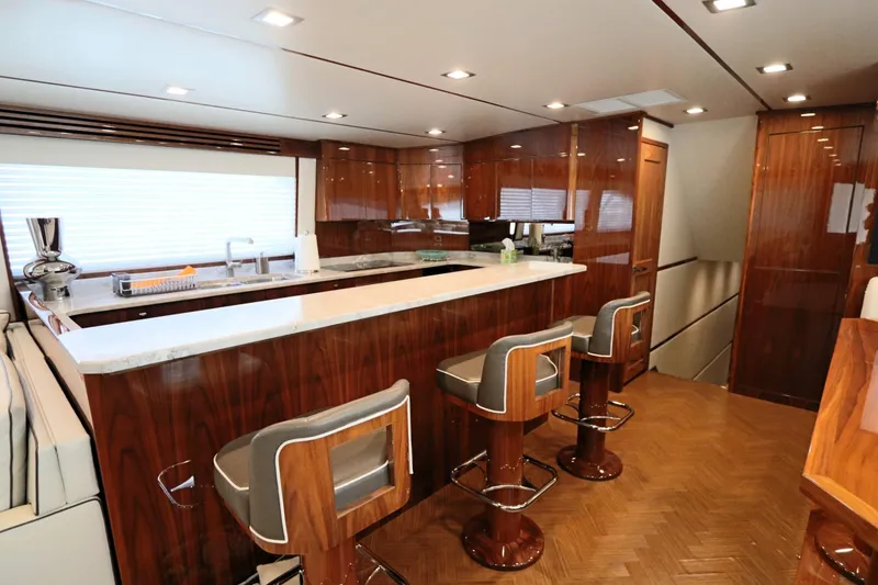 Slide: The Image of Luxurious interior of 2017 Viking 80 Enclosed Bridge yacht with modern kitchen and bar stools. - 7