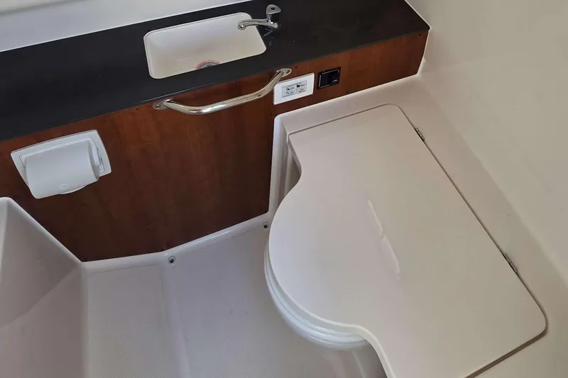 Slide: The Image of 2025 Pursuit S 288 Sport boat interior with sink and closed toilet lid. - 14