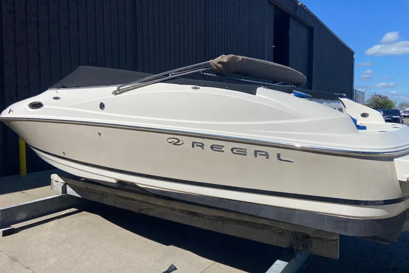 The Image of 2005 Regal 2400 Bowrider boat on trailer, parked outdoors under blue sky. - 4