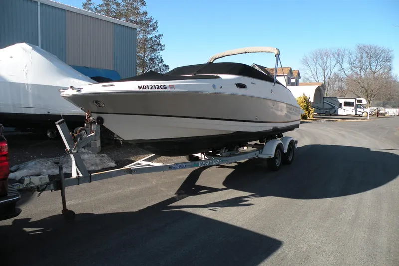 Slide: The Image of 2005 Regal 2400 Bowrider boat on trailer, parked outdoors on a sunny day. - 7