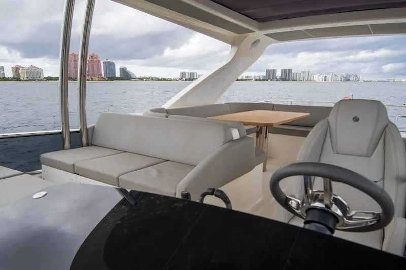 Slide: The Image of 2023 Absolute 62 Fly yacht interior with seating, table, and steering wheel, overlooking waterfront skyline. - 27