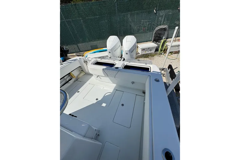 Slide: The Image of 2025 Contender 30 Tournament boat interior with dual outboard motors, docked near a fence. - 23