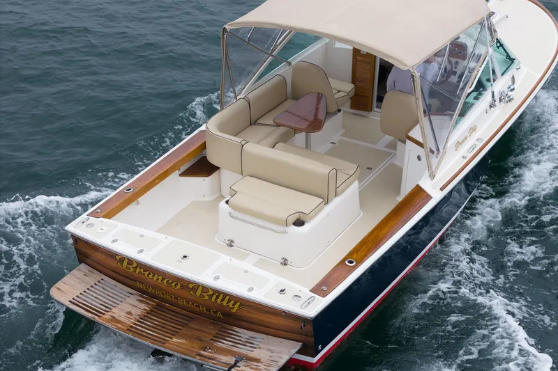 Slide: The Image of 2006 Hunt Yachts Harrier 25 cruising on water, featuring beige seating and canopy. - 14