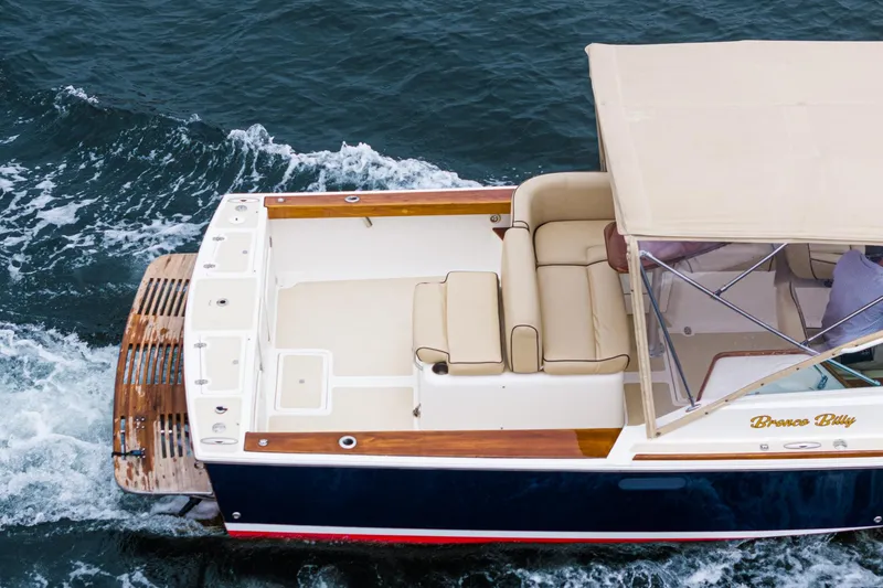 Slide: The Image of 2006 Hunt Yachts Harrier 25 cruising on water, featuring beige seating and canopy. - 16