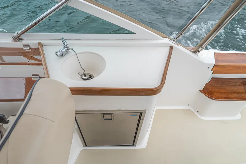 Slide: The Image of 2006 Hunt Yachts Harrier 25 interior with sink and storage, featuring elegant wood accents. - 24