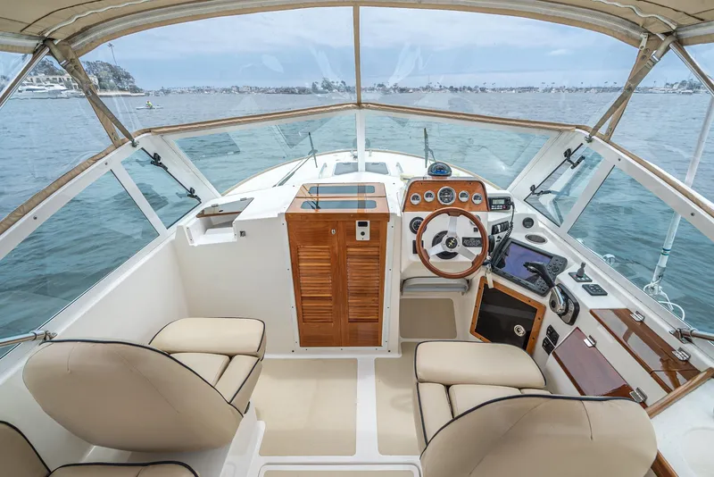 Slide: The Image of 2006 Hunt Yachts Harrier 25 cockpit with beige seating and wooden dashboard on open water. - 25
