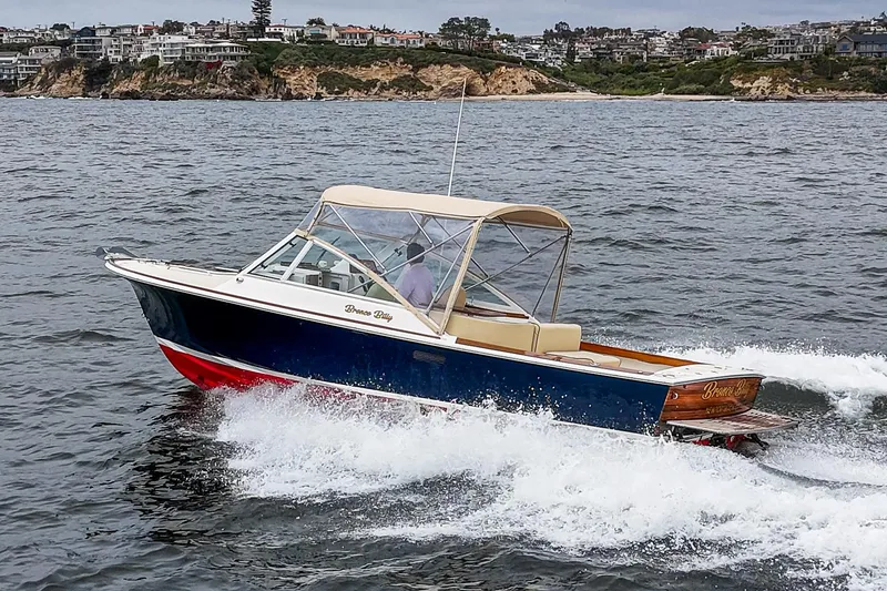 Slide: The Image of 2006 Hunt Yachts Harrier 25 cruising on the water near a coastal town. - 4