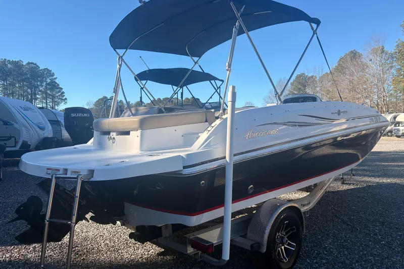 Slide: The Image of 2015 Hurricane SunDeck Sport 188 IO boat on trailer, parked outdoors. - 2