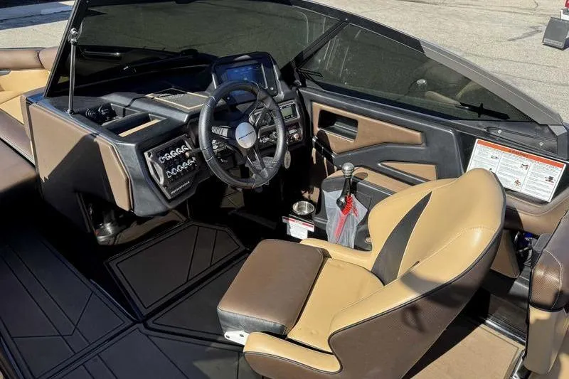 Slide: The Image of 2021 Moomba Makai boat interior with steering wheel, dashboard, and tan seating. - 13