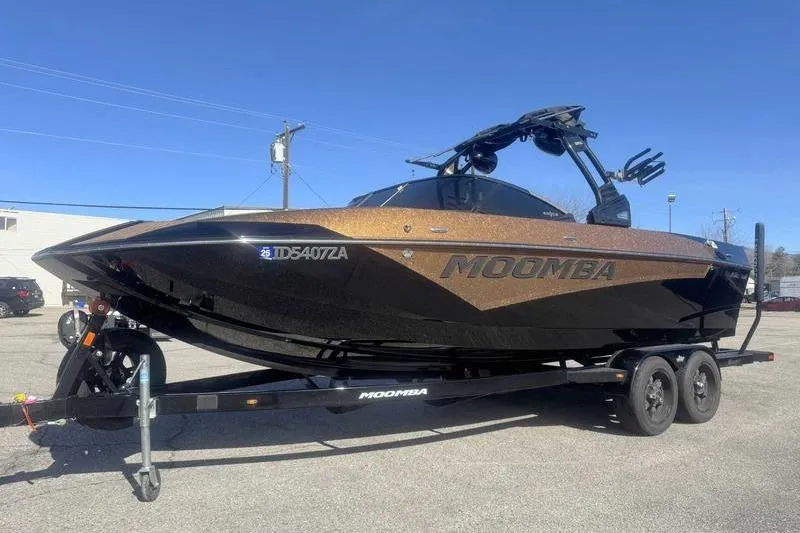 Slide: The Image of 2021 Moomba Makai boat on trailer, black and bronze, parked outdoors. - 4