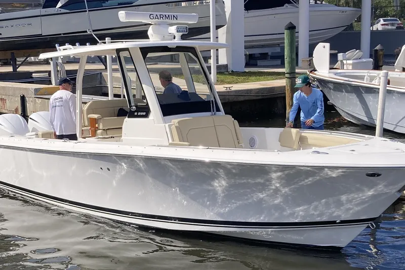 Slide: The Image of 2019 Pursuit S 288 Sport boat docked with people onboard, featuring Garmin equipment. - 12
