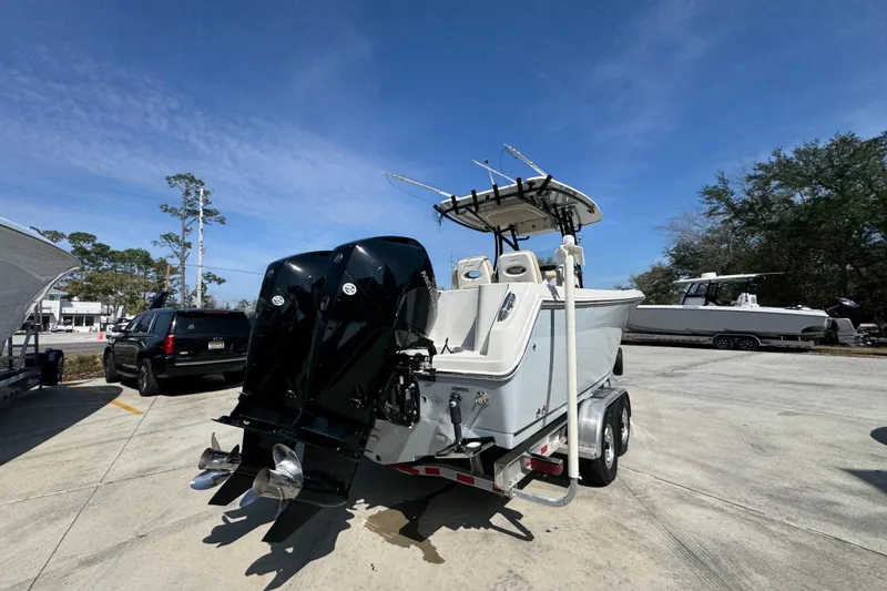 Slide: The Image of 2019 Sailfish 270 CC boat on trailer with dual engines, parked outdoors under clear sky. - 11