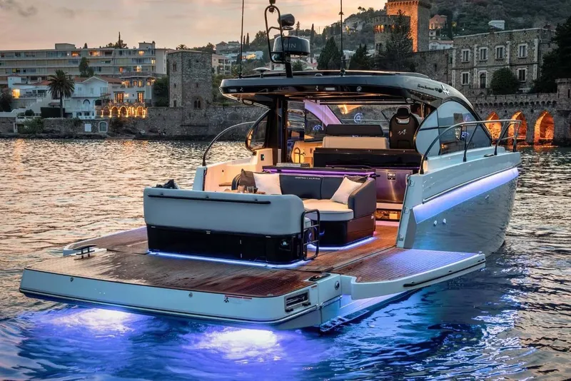 Slide: The Image of Manufacturer Provided Image: 2025 Beneteau Gran Turismo 40 yacht with illuminated deck, docked near historic buildings at sunset. - 4