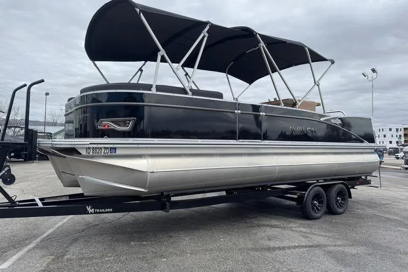 Slide: The Image of 2025 Avalon 2585 25 Catalina ENT pontoon boat on trailer, black exterior, parked outdoors. - 3