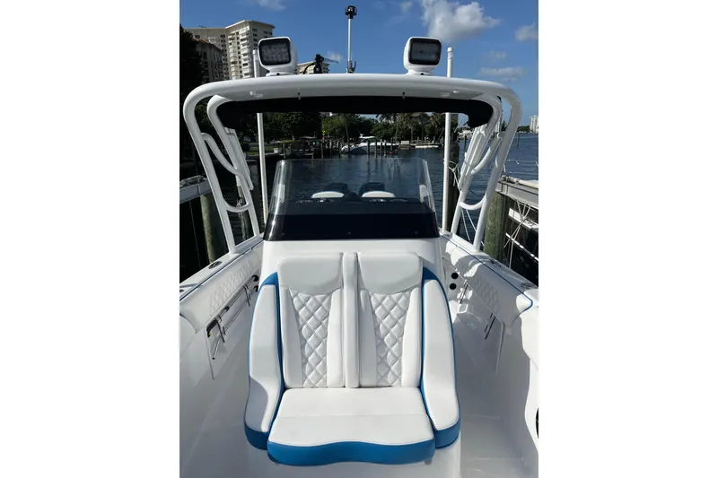 Slide: The Image of 2023 Renegade 32' Cuddy boat interior with white and blue seating, docked by the water. - 5