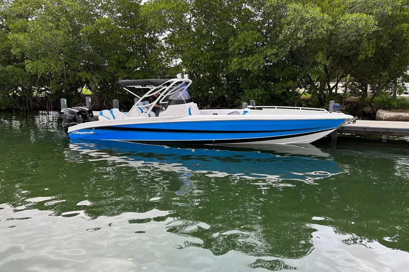 Slide: The Image of 2023 Renegade 32' Cuddy boat docked on calm water, surrounded by lush greenery. - 6