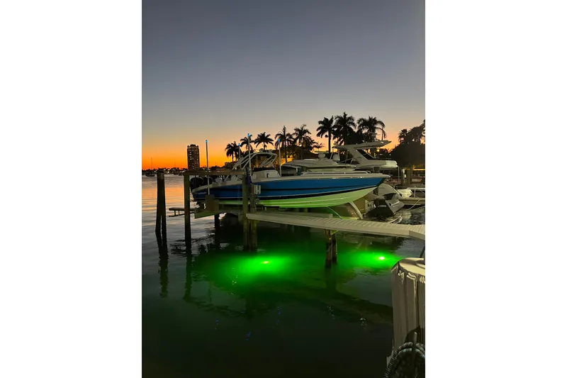 Slide: The Image of 2023 Renegade 32' Cuddy boat docked at sunset with green underwater lights. - 8