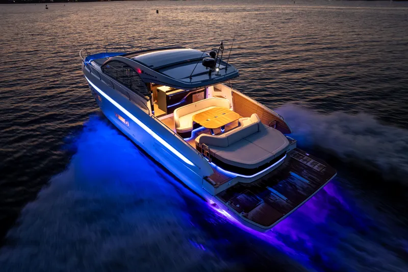 Slide: The Image of 2026 Beneteau Gran Turismo 50 yacht cruising at sunset with vibrant blue underwater lights. - 0