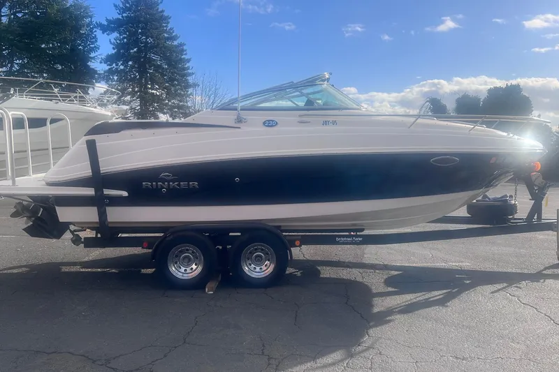 Slide: The Image of 2007 Rinker 230 Captiva Atlantic boat on trailer, parked outdoors under a sunny sky. - 11