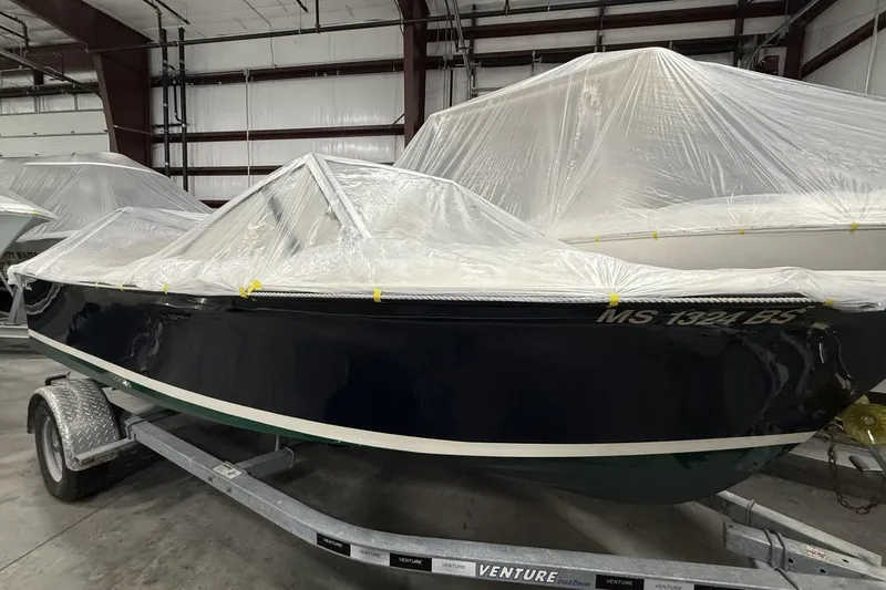 Slide: The Image of 2022 Rossiter 17 Closed Deck boat covered in plastic, stored indoors on a trailer. - 7