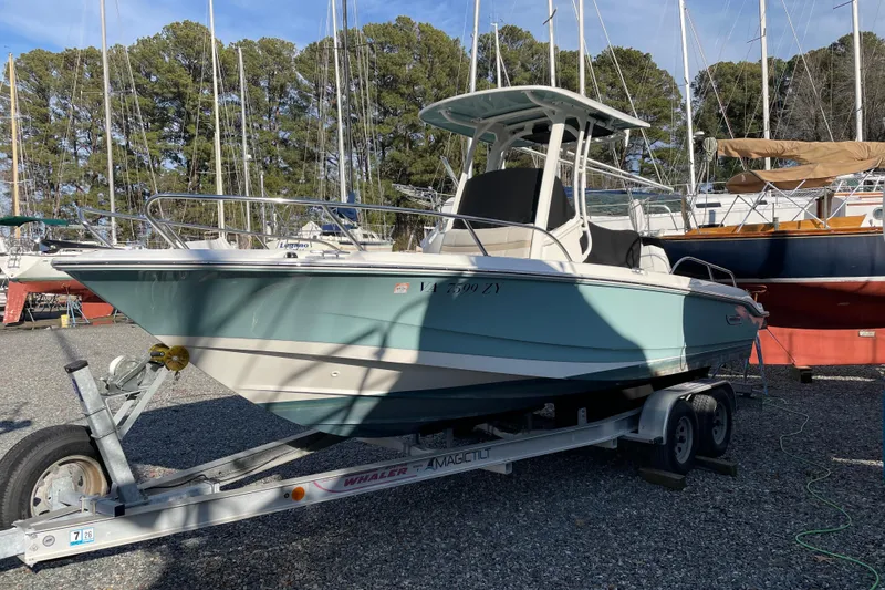 Slide: The Image of 2023 Boston Whaler 220 Dauntless boat on trailer, surrounded by sailboats and trees. - 10