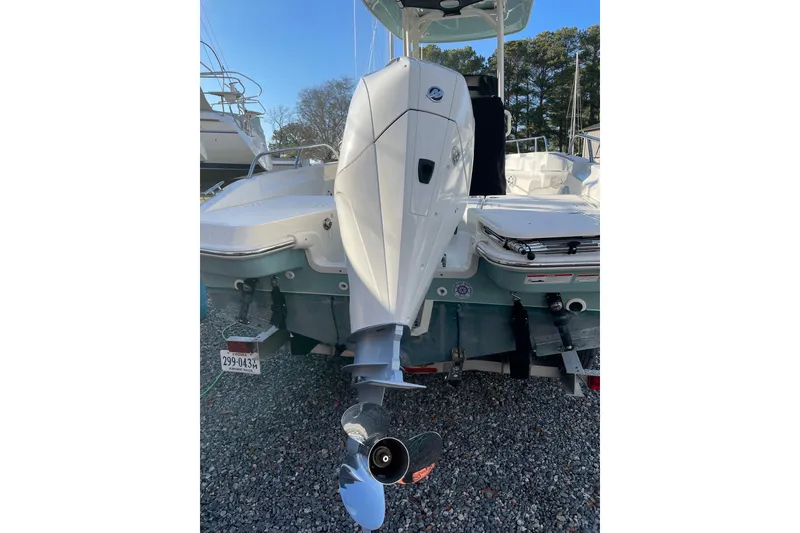 Slide: The Image of 2023 Boston Whaler 220 Dauntless boat, rear view with outboard motor, on gravel surface. - 7