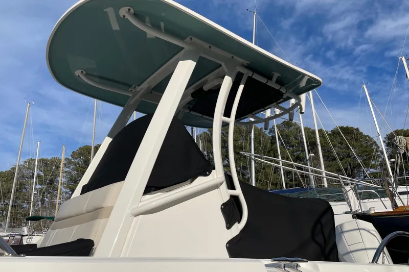 Slide: The Image of 2023 Boston Whaler 220 Dauntless boat with T-top, docked under clear blue sky. - 9