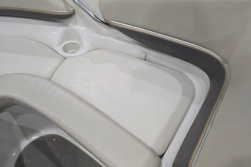Slide: The Image of 2004 Larson LXi 190 boat interior seating with cup holder, featuring white and gray upholstery. - 21