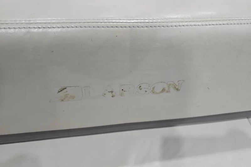 Slide: The Image of 2004 Larson LXi 190 boat seat with worn logo on white upholstery. - 31