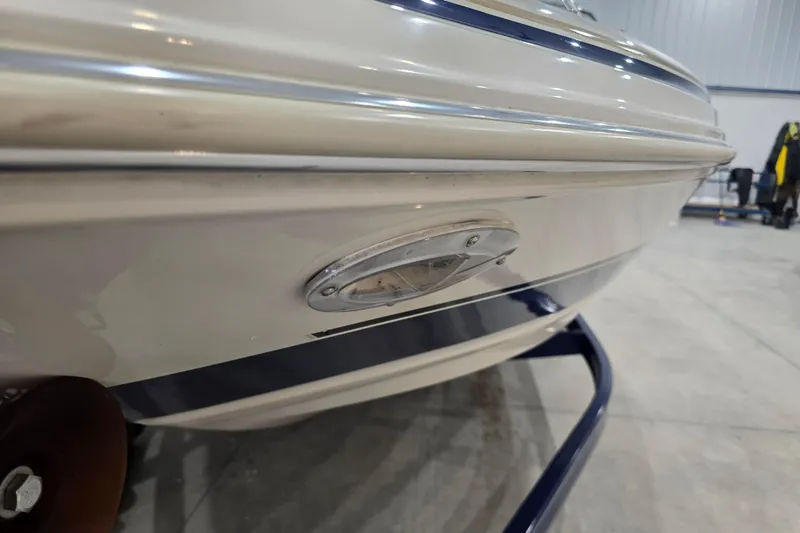 Slide: The Image of 2004 Larson LXi 190 boat close-up, showcasing hull and light detail in a garage setting. - 34