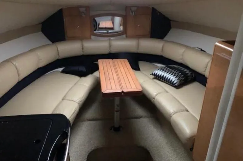 Slide: The Image of 2013 Glastron GS 289 cabin interior with beige seating and wooden table. - 5