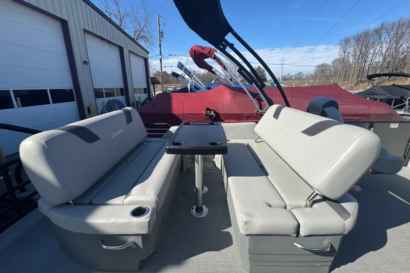 Slide: The Image of 2025 Sylvan L3 DLZ pontoon boat with gray seating and table, parked outdoors. - 13