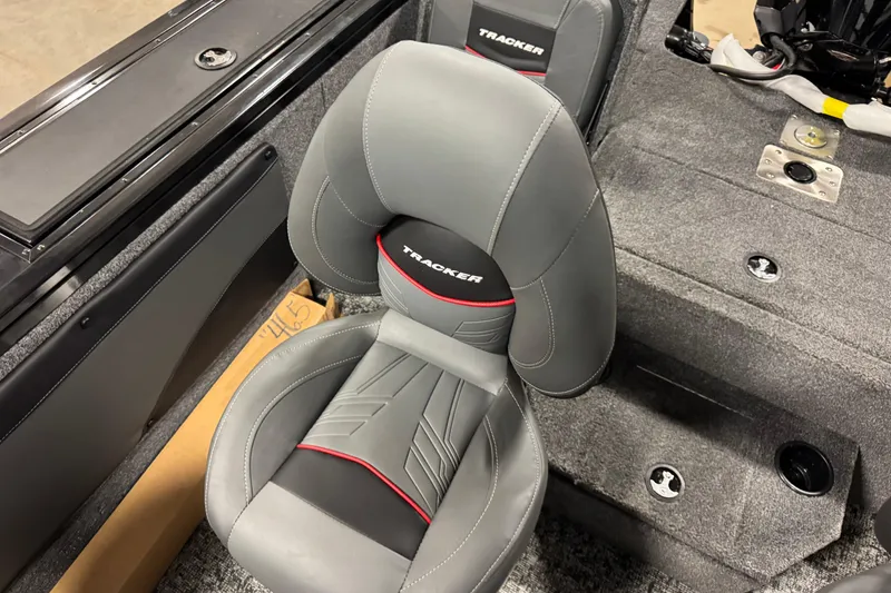 Slide: The Image of 2026 Tracker Targa V-19 Combo boat seat, gray with red accents, in a carpeted interior. - 13