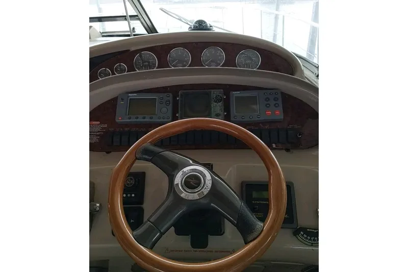 Slide: The Image of 2004 Sea Ray 380 Sundancer helm with gauges and wooden steering wheel. - 11