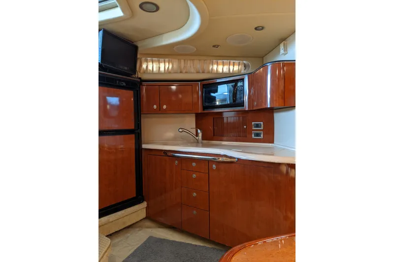Slide: The Image of 2004 Sea Ray 380 Sundancer yacht interior kitchen with wood cabinetry and modern appliances. - 17