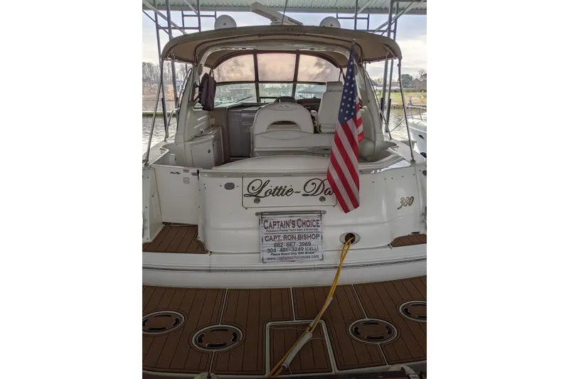 Slide: The Image of 2004 Sea Ray 380 Sundancer docked, displaying American flag and "Lottie-Da" name. - 2