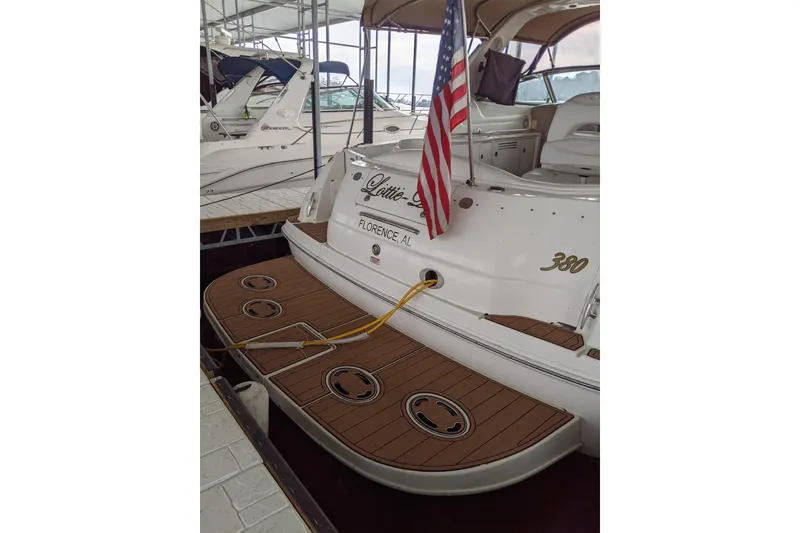 Slide: The Image of 2004 Sea Ray 380 Sundancer docked, featuring a wooden deck and American flag. - 40