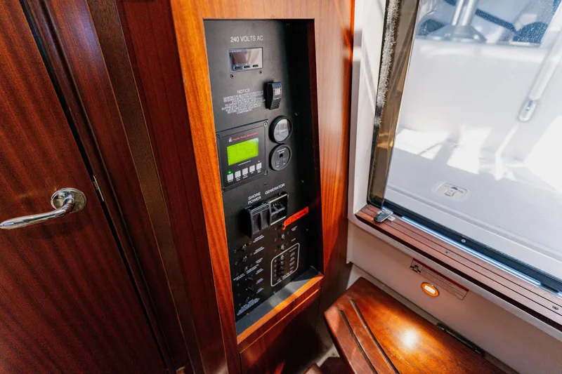 Slide: The Image of 2022 Pursuit S 378 Sport electrical panel with wooden finish and window view. - 56