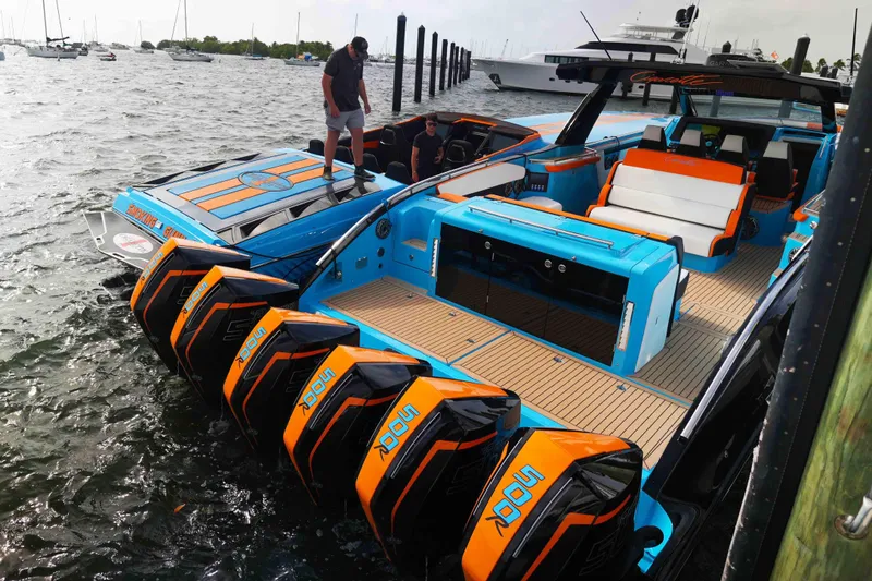 Slide: The Image of 2024 Cigarette 59' Tirranna boat with vibrant blue and orange design, docked in marina. - 4