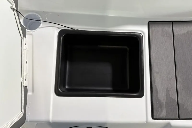 Slide: The Image of 2026 Tahoe T16 boat storage compartment with black interior and adjacent wooden panel. - 21