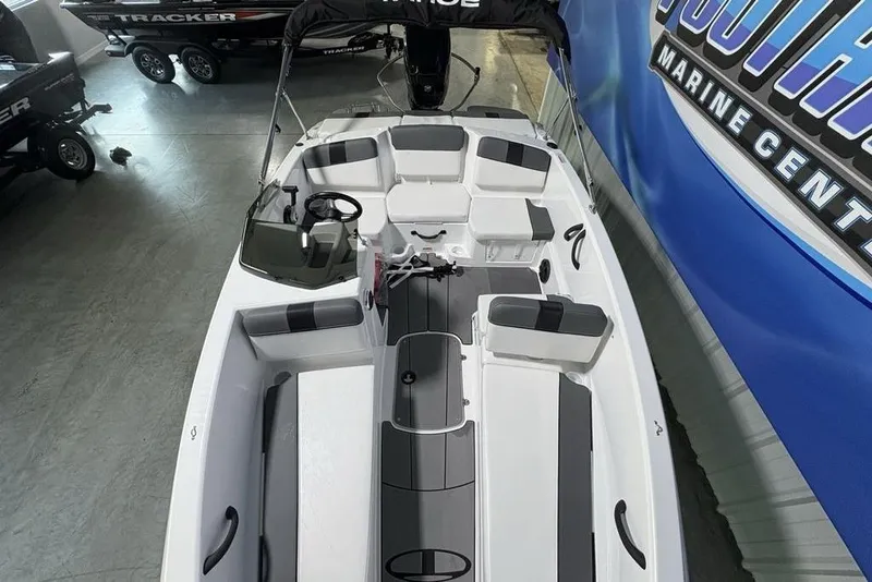 Slide: The Image of 2026 Tahoe T16 boat interior with seating and steering wheel, displayed at a marine center. - 22