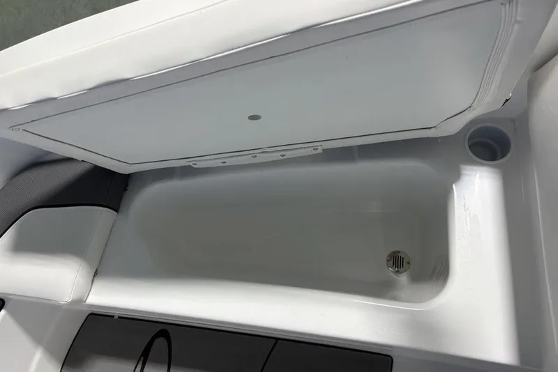Slide: The Image of Open storage compartment in 2026 Tahoe T16 boat, featuring a drain plug. - 7