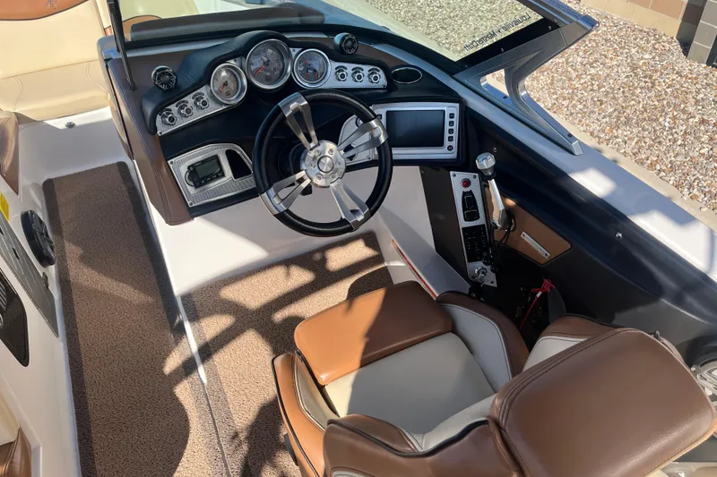 Slide: The Image of 2016 MasterCraft X23 boat cockpit with modern controls and brown leather seating. - 10