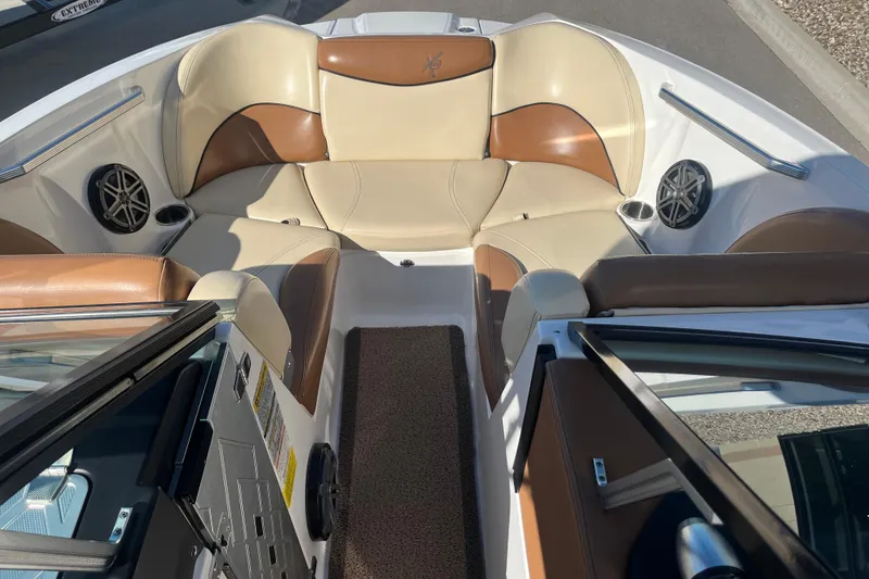 Slide: The Image of 2016 MasterCraft X23 boat interior with tan and brown seating, cup holders, and speakers. - 12
