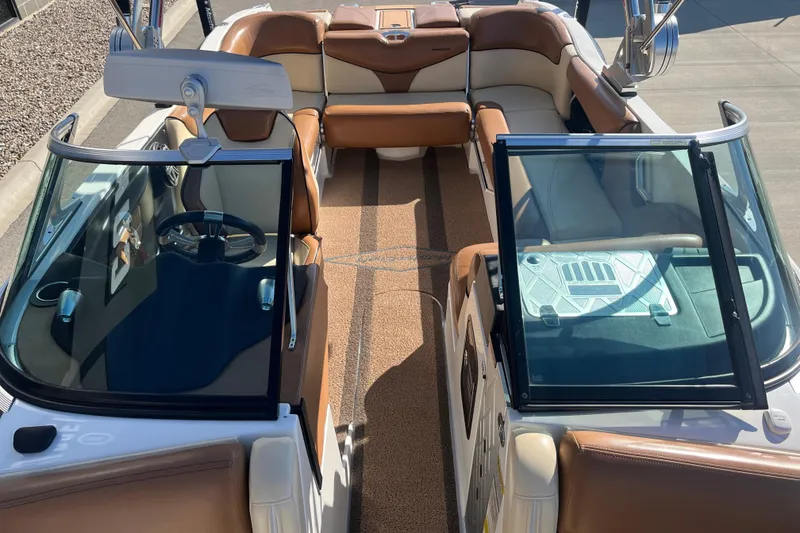 Slide: The Image of 2016 MasterCraft X23 boat interior with brown and white seating, steering wheel, and open windshield. - 13