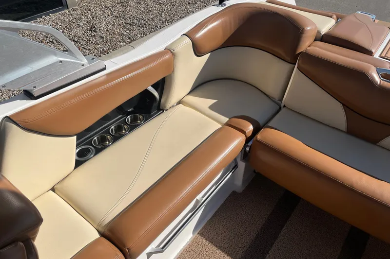 Slide: The Image of 2016 MasterCraft X23 boat interior with tan and brown leather seats, featuring built-in cup holders. - 16