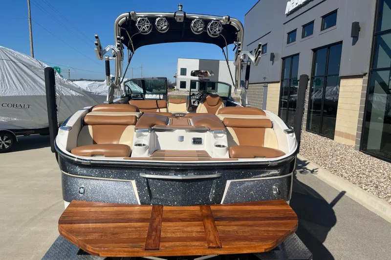 Slide: The Image of 2016 MasterCraft X23 boat with brown seating and wooden swim platform, parked outdoors. - 8