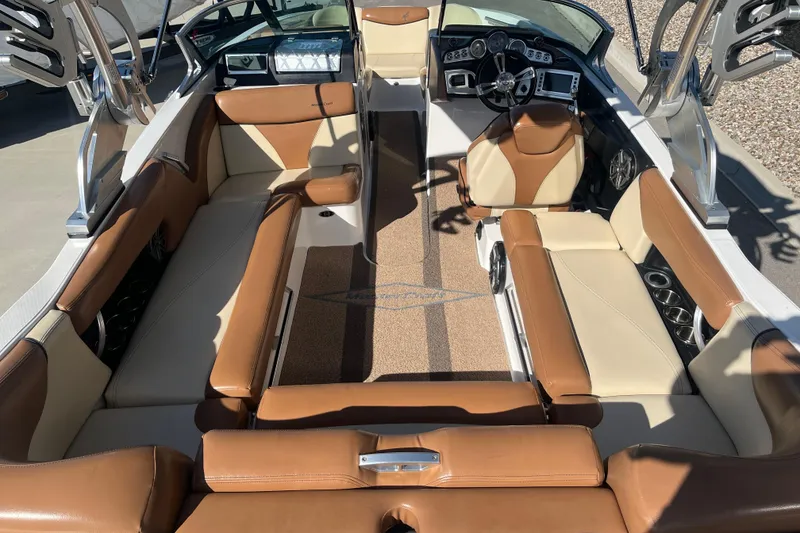 Slide: The Image of 2016 MasterCraft X23 boat interior with brown and cream seating, modern dashboard, and spacious layout. - 9